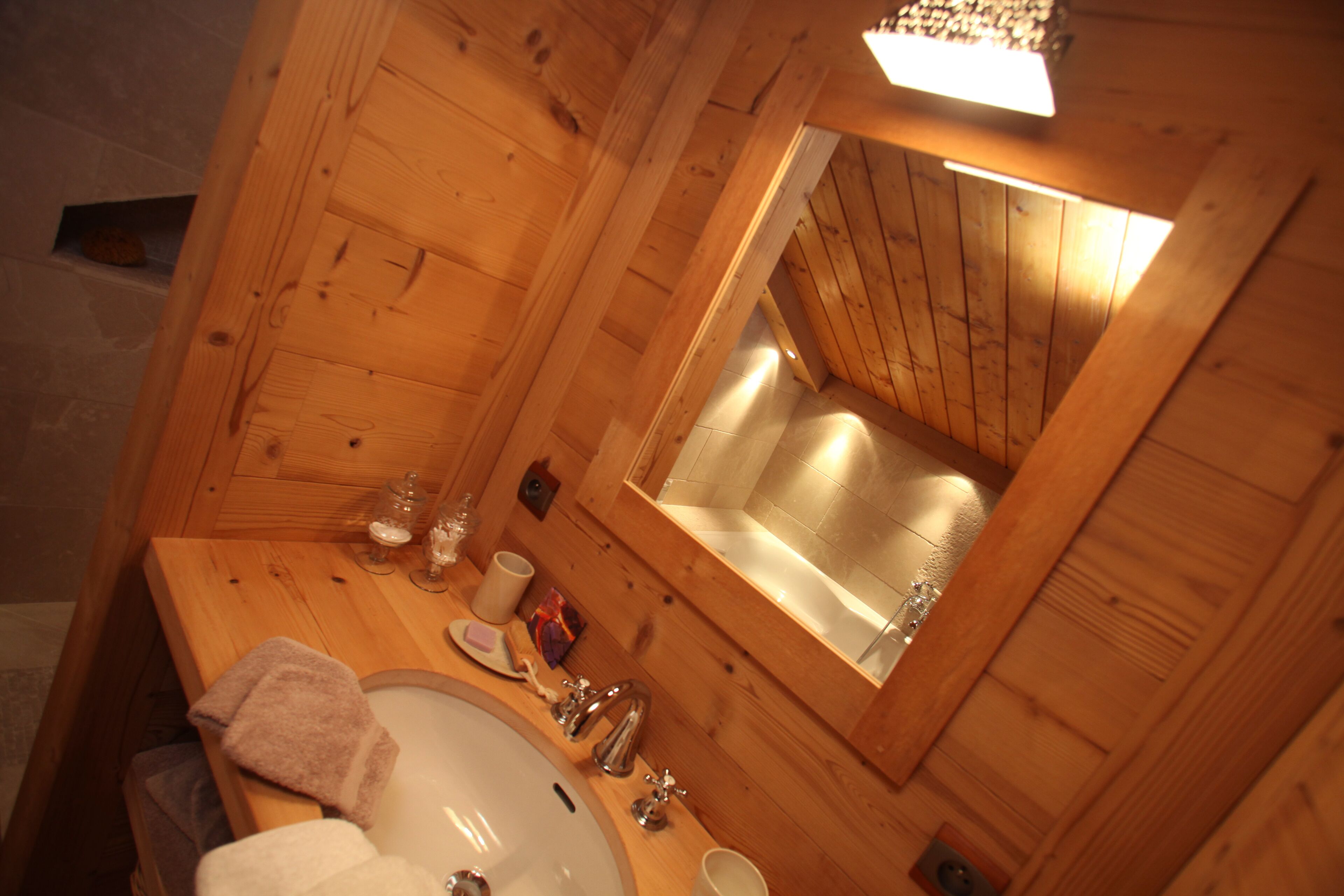 A wooden cabin bathroom with a sink, mirror, and towel.