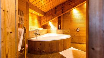 A wooden cabin bathroom with a freestanding bathtub, wooden walls, and a wooden floor.