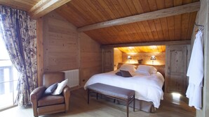 A wooden cabin bedroom with a bed, a chair, a bench, and a window with curtains. - Maison d'hôtes Le Pré Oudot (Fournets-Luisans)