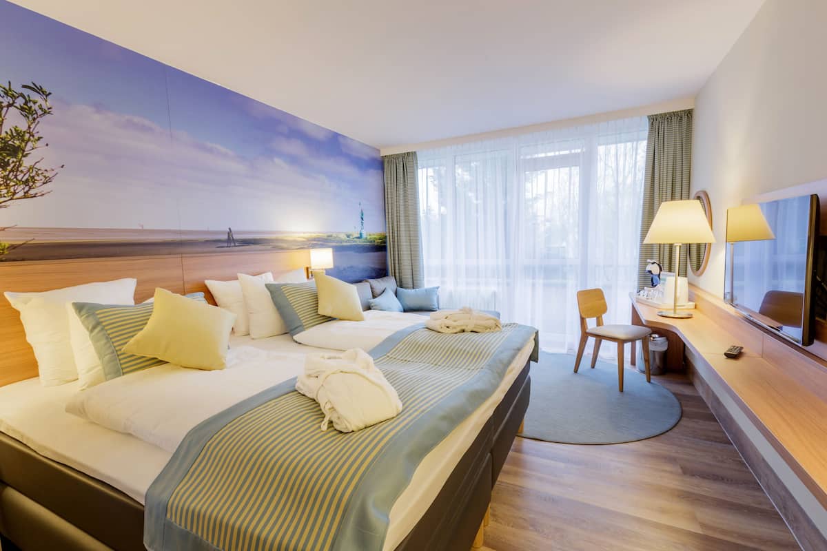 Hotelkamer met een groot bed, een bureau, een stoel, een televisie en een landschapsschilderij.