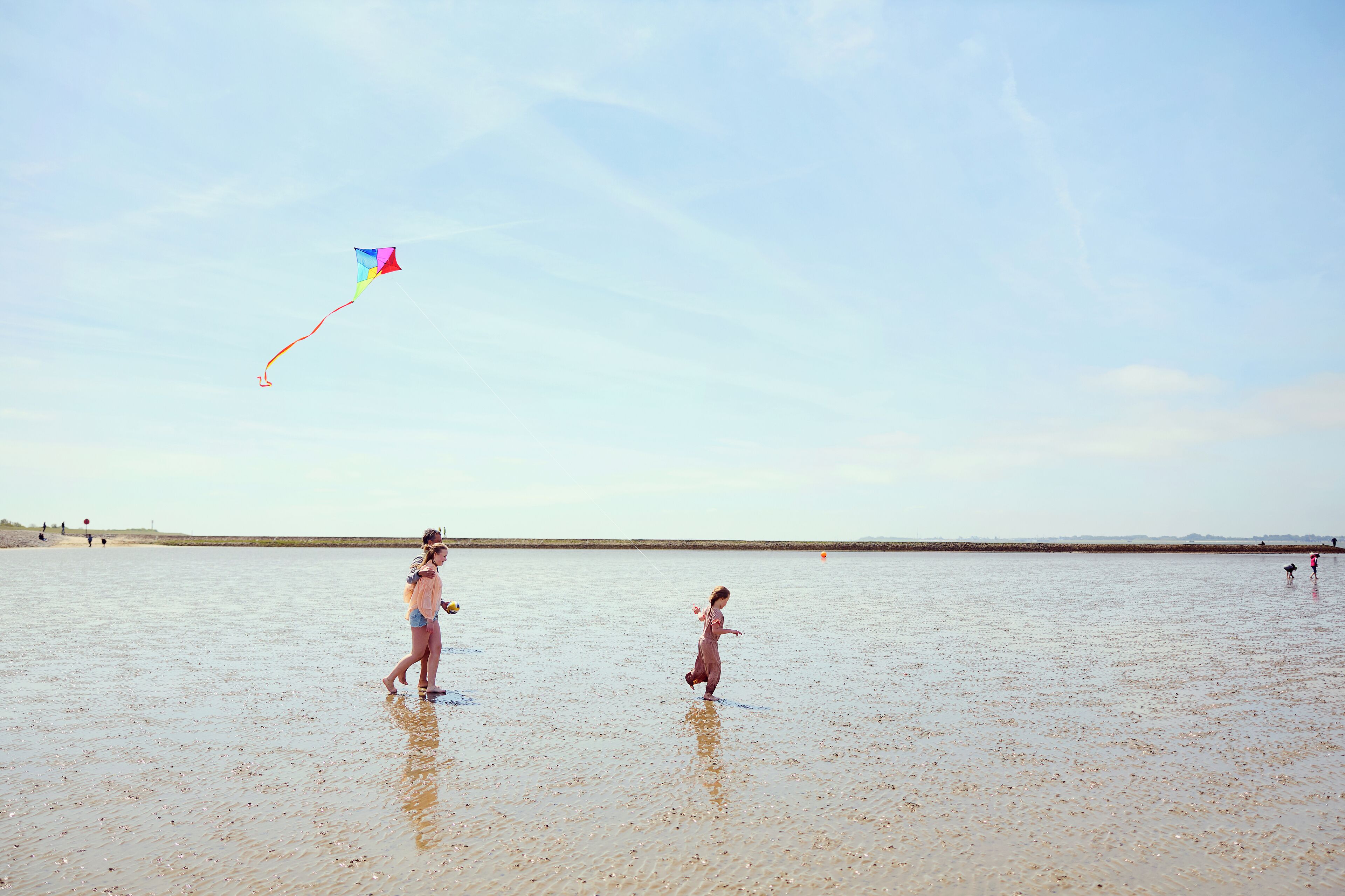 Escena de playa con un niño volando una cometa.