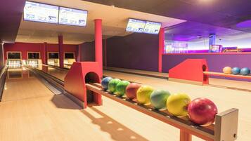 A bowling alley with multiple lanes, a bowling ball return system, and overhead digital scoreboards.