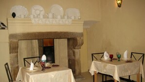 Ein Essbereich mit zwei gedeckten Tischen, einem Kamin und einem dekorativen Regal darüber.