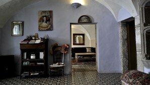 Ein Zimmer mit hoher, gewölbter Decke, einem Holzstuhl, einem kleinen Tisch und einem gemusterten Boden.
