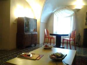 A dining area with a table, chairs, and a television. - Casa rural La Cantarera (Herguijuela)
