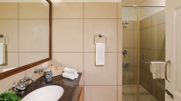 A bathroom with a sink, mirror, and a shower area.