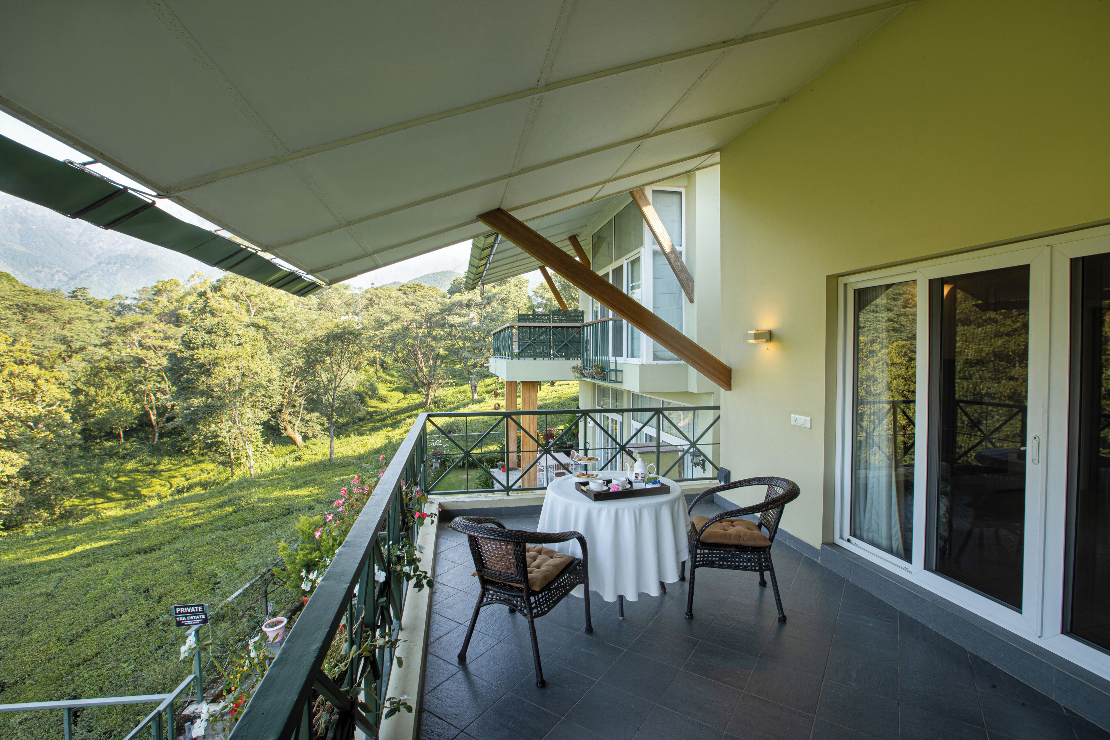 Uma varanda com mesa e cadeiras, com vista para uma paisagem verdejante.