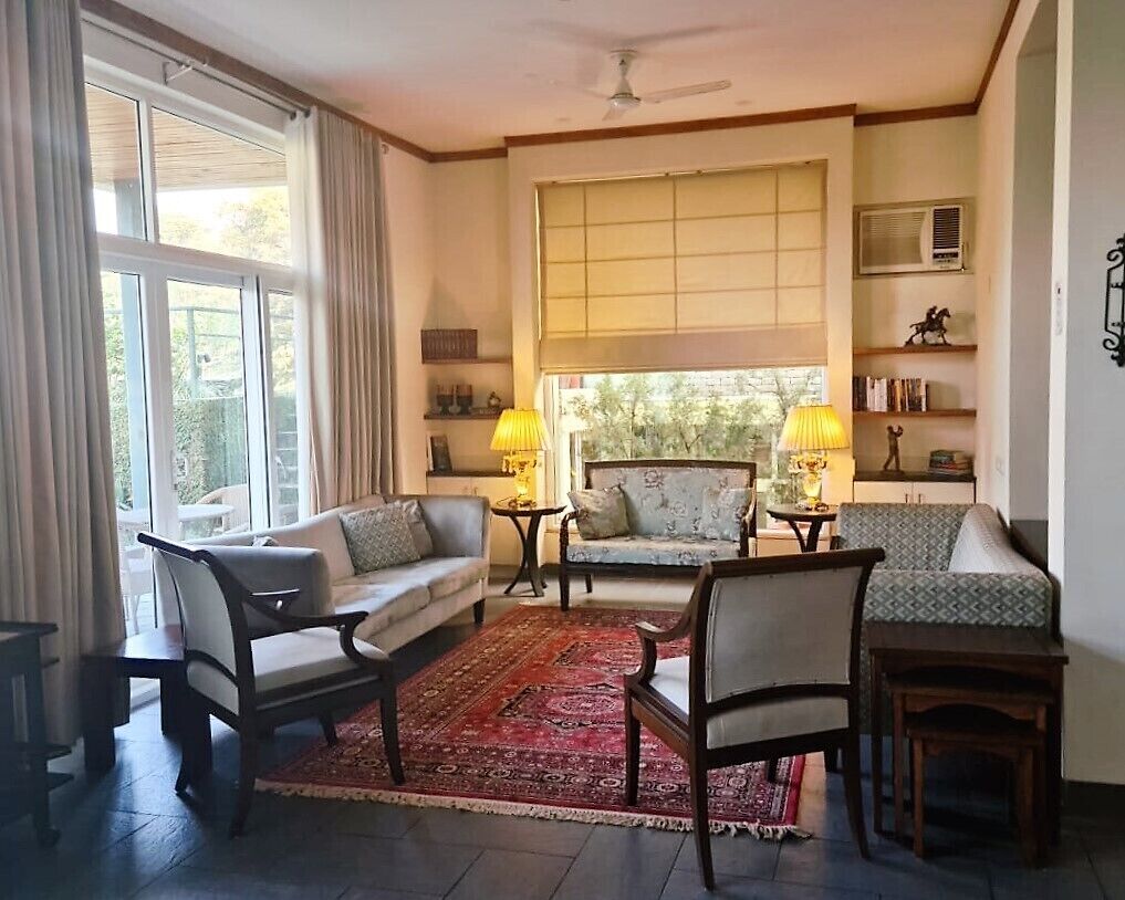 A living room with a sofa, chairs, a coffee table, a rug, and a window with curtains.