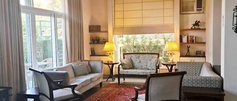 A living room with a sofa, chairs, a coffee table, a rug, and a window with curtains.