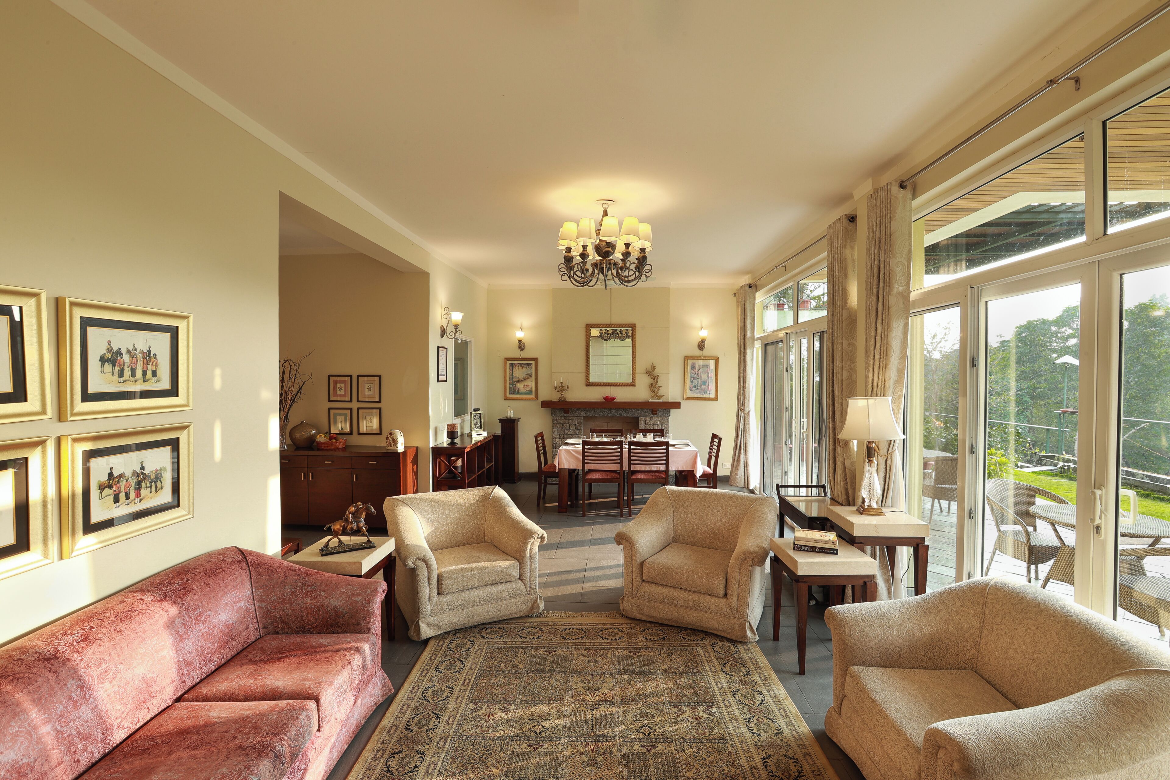 A spacious living room with a fireplace, comfortable seating, and large windows offering a view of the outdoors.