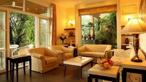 A spacious living room with large windows, a sofa set, a coffee table, and a lamp. - Lamrin Norwood Green Palampur (Palampur)