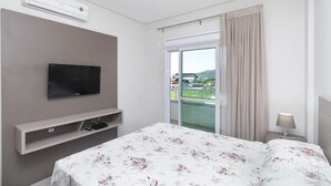 Une chambre d’hôtel équipée d’un lit, d’un téléviseur fixé au mur, d’une fenêtre avec des rideaux et d’un appareil de climatisation.