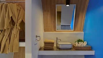 Une salle de bain avec un meuble-lavabo en bois, un évier, un miroir et un porte-serviettes avec des peignoirs.