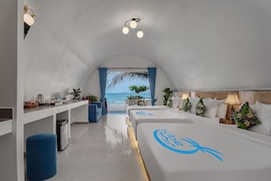 A modern hotel room with a view of the ocean, a kitchenette, a sitting area, and a bed with a logo. - Tube Resort by EHM (Koh Rong Sanloem)