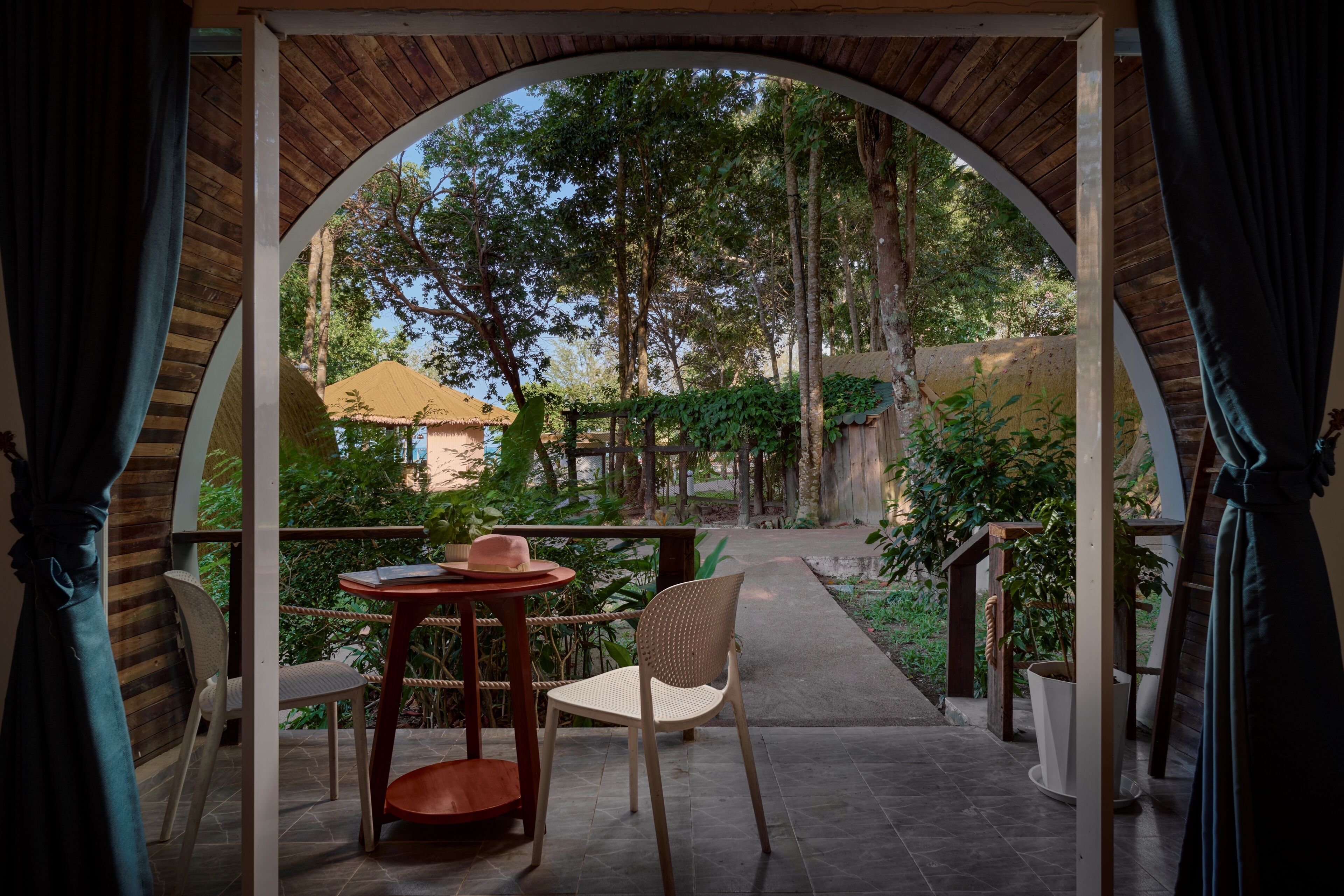 An outdoor seating area with a table and chairs, surrounded by a wooden archway.