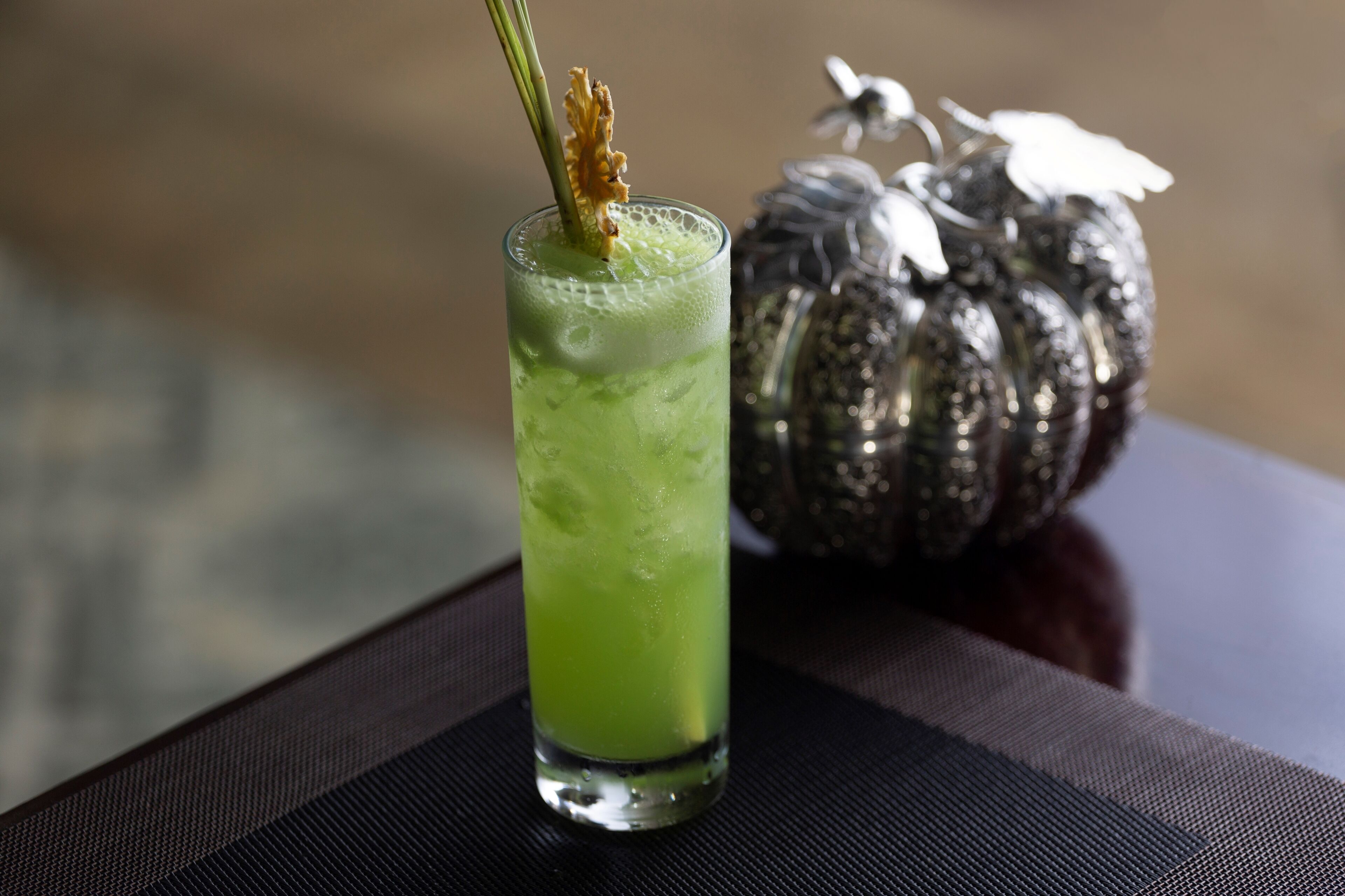 Een glas groen drankje met garnering op een tafel.