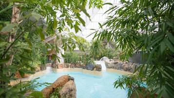 An indoor swimming pool surrounded by rocks and greenery.