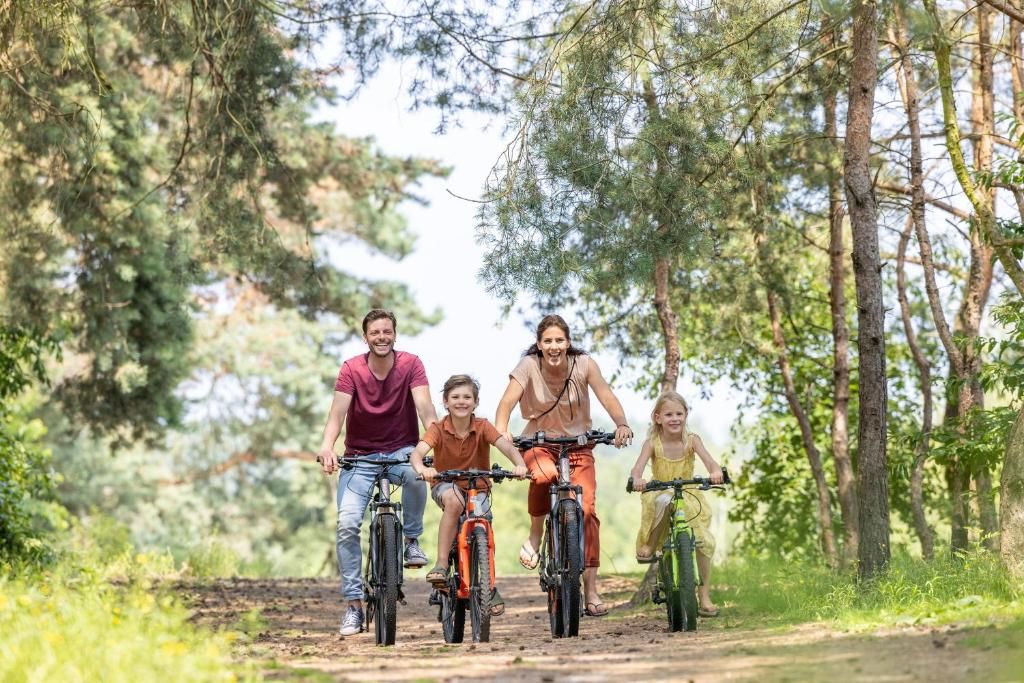A family on a dirt path surrounded by trees.