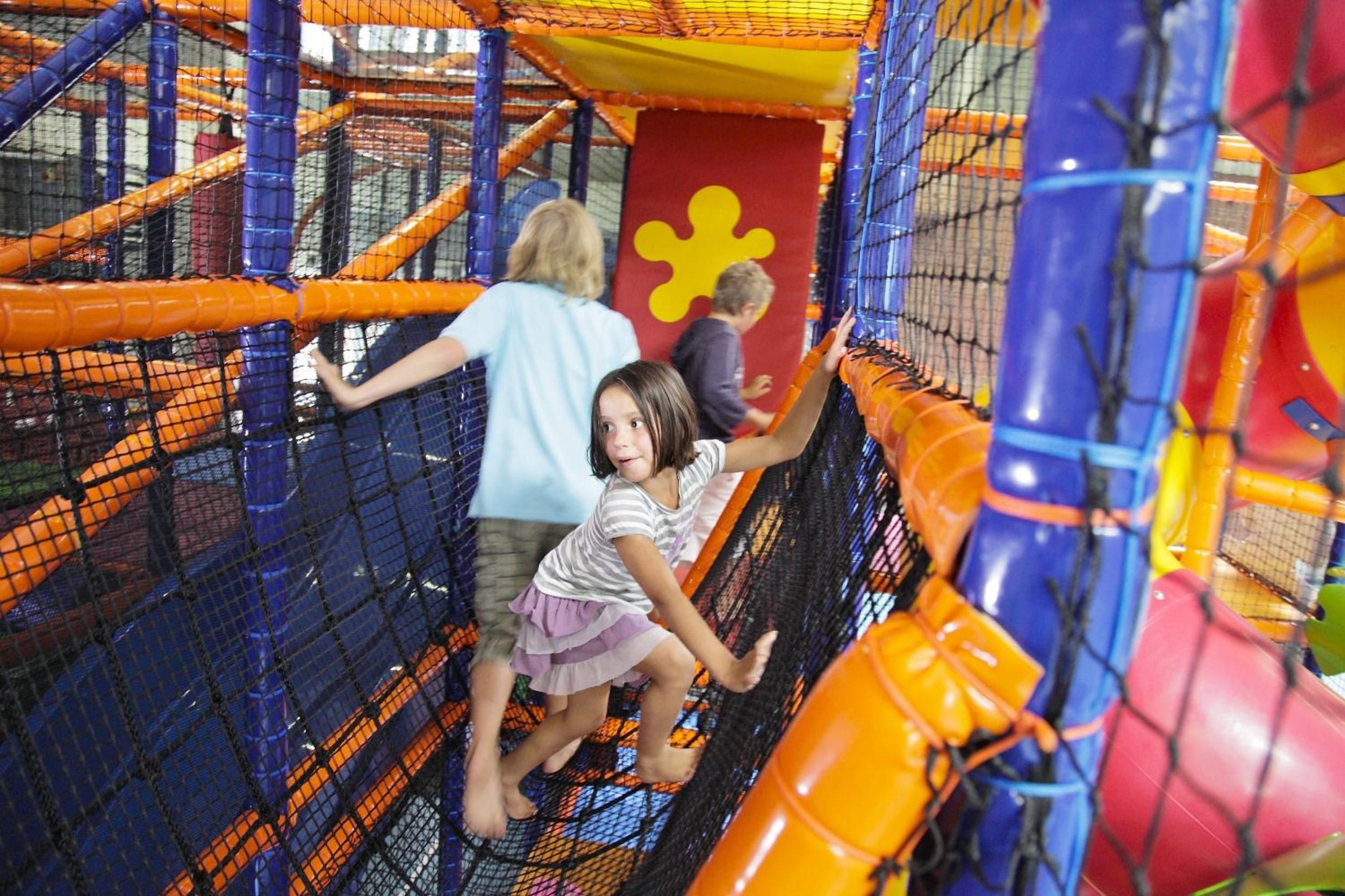 An indoor play area with netted climbing structures and colorful play equipment.