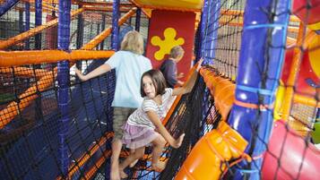 An indoor play area with netted climbing structures and colorful play equipment.