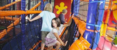 An indoor play area with netted climbing structures and colorful play equipment.