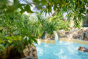 A pool area with clear blue water, surrounded by rocks and lush greenery. - Hotel Sunparks Kempense Meren (Mol)