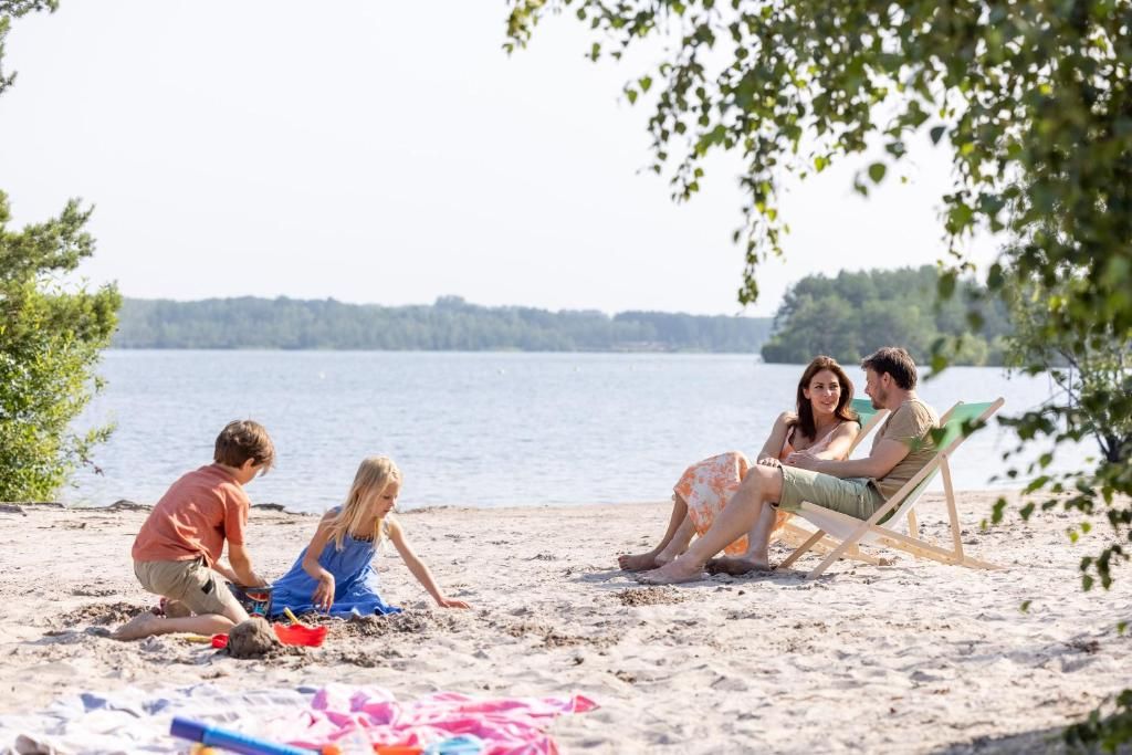 Une scène de plage où l’on voit des gens, dont des enfants qui jouent dans le sable et des adultes qui se détendent sur des chaises.