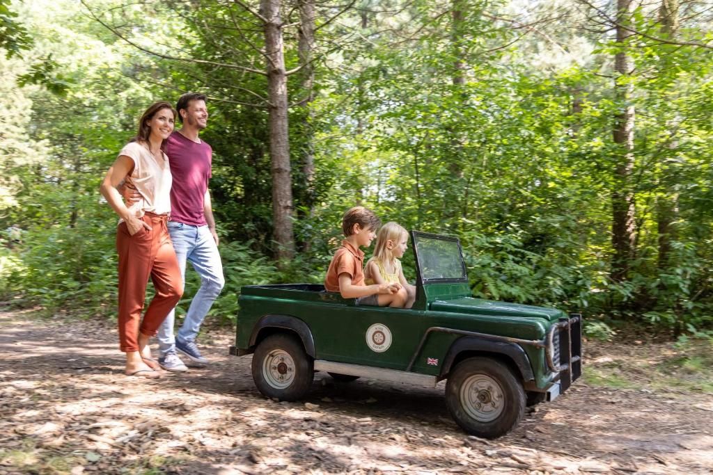 Ein grünes Fahrzeug mit einer Person darin, geparkt auf einem Waldweg.