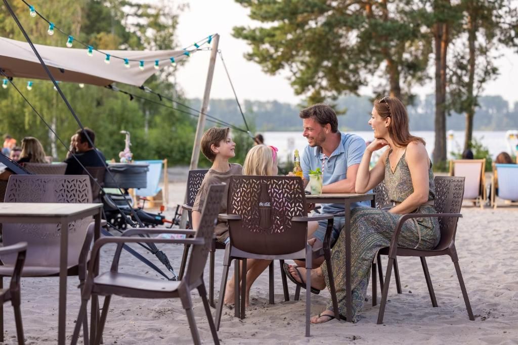 An outdoor dining area with tables and chairs, a tent, and string lights.
