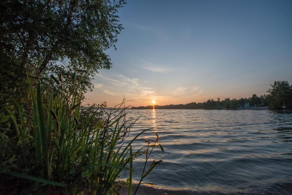 A sunset over a calm body of water with trees on the left.