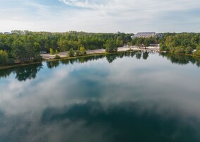 A calm lake with a reflection of trees and a building in the background.