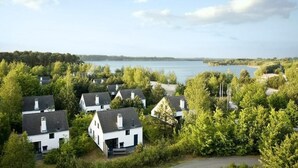 Un barrio residencial con casas rodeadas de árboles y un lago al fondo.