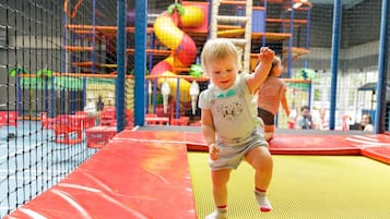 Niño jugando en un trampolín dentro de un área de juegos con cerramiento de red.