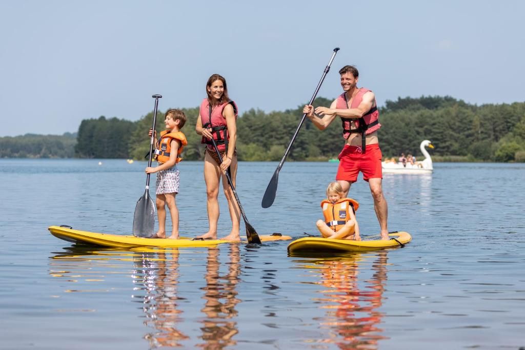 Un grupo de personas en tablas de paddleboard en un lago tranquilo, con un bote al fondo.