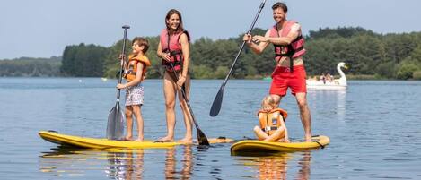 A group of people on paddleboards in a calm lake with a boat in the background.