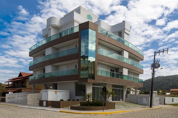 A multi-story building with a modern design, featuring glass balconies and a mix of brick and concrete materials.