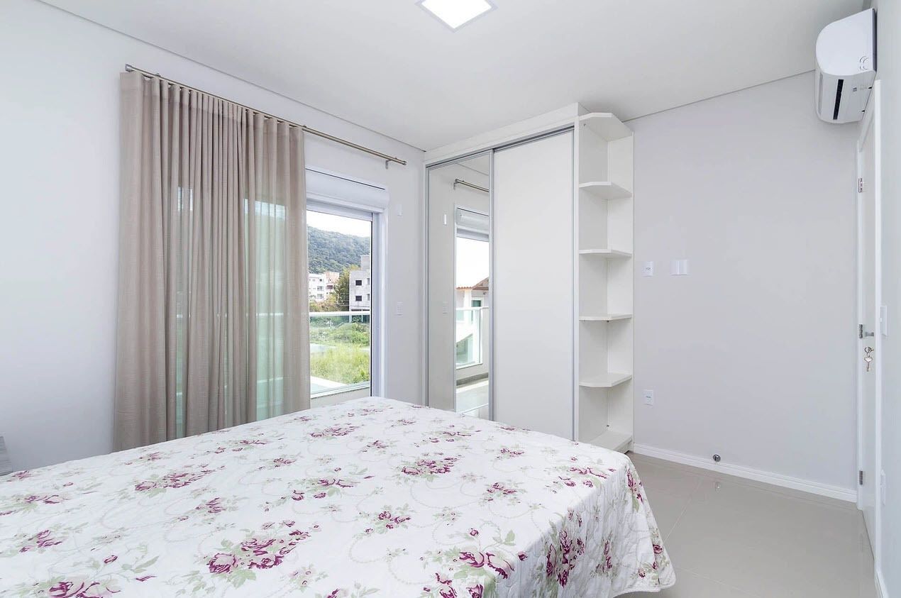 A bedroom with a bed, a sliding door to a balcony, and a built-in shelf unit.