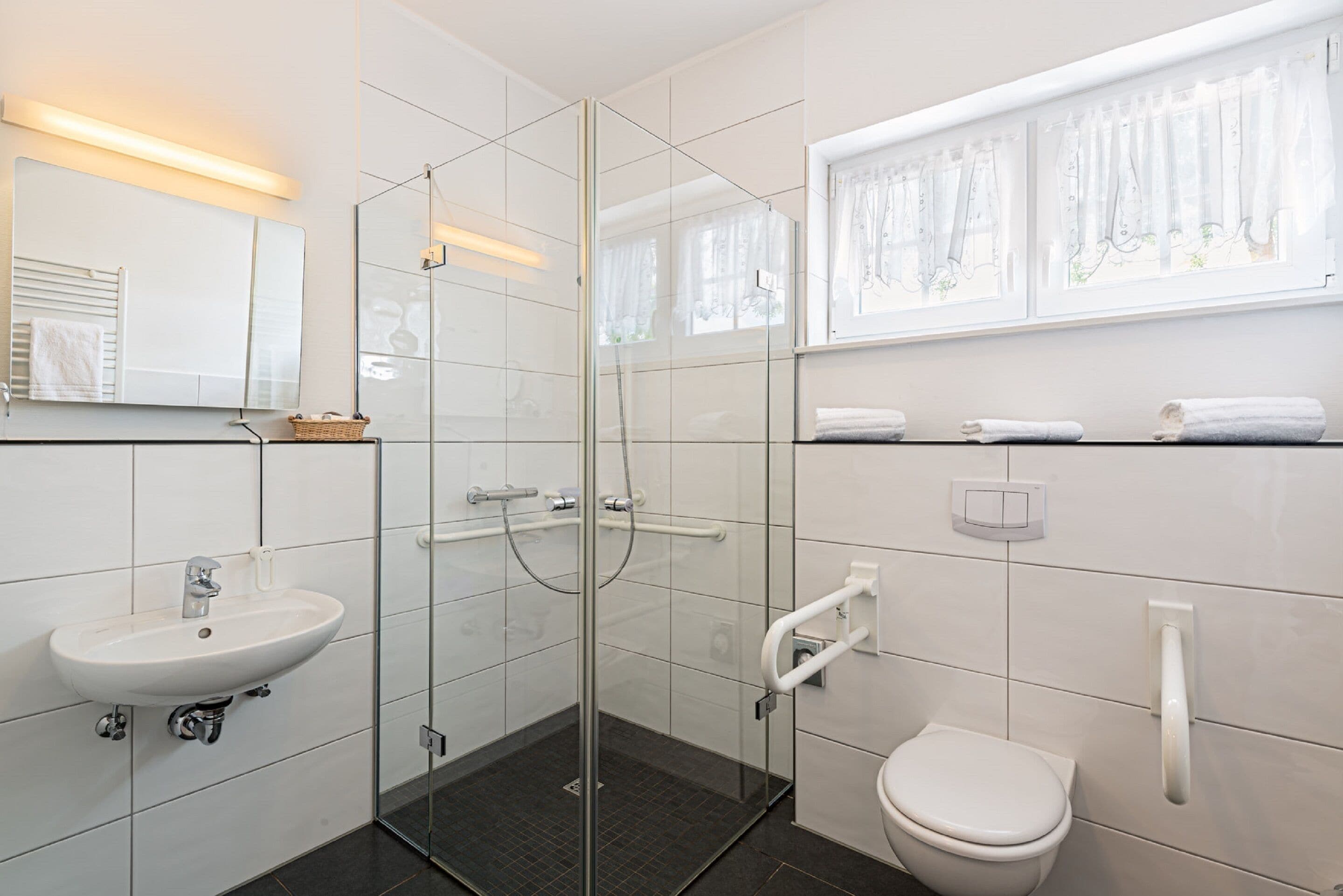 A modern bathroom with a glass-enclosed shower, a white sink, and a toilet.