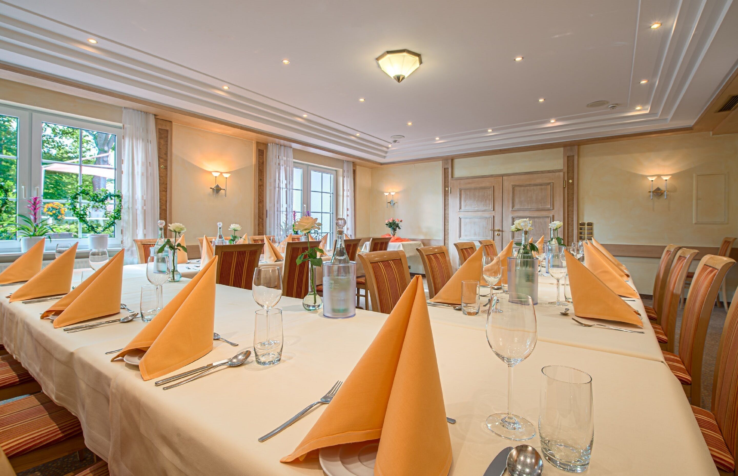 A long dining table set for a formal event with multiple place settings, including plates, cutlery, and glasses.