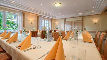 A long dining table set for a formal event with multiple place settings, including plates, cutlery, and glasses.