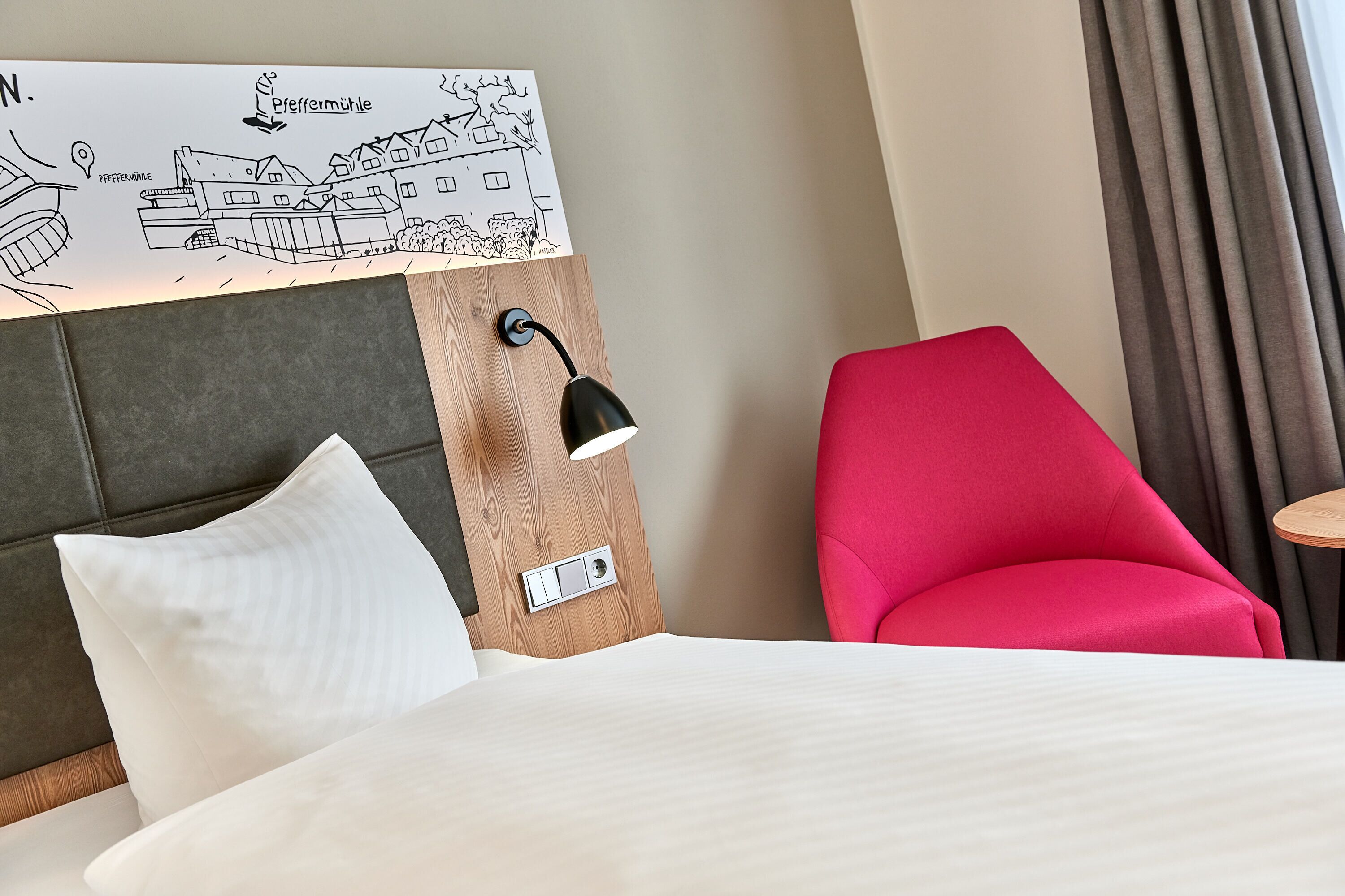 Habitación de hotel con cama, una silla roja, una lámpara de pared y un mapa de Pfeffermühle.