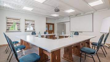 Un salón de conferencias con una larga mesa, seis sillas y una pantalla de proyector.