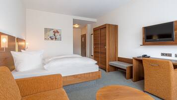 Une chambre d’hôtel avec un lit, un canapé, un bureau, une chaise, une télévision et un tableau au mur.