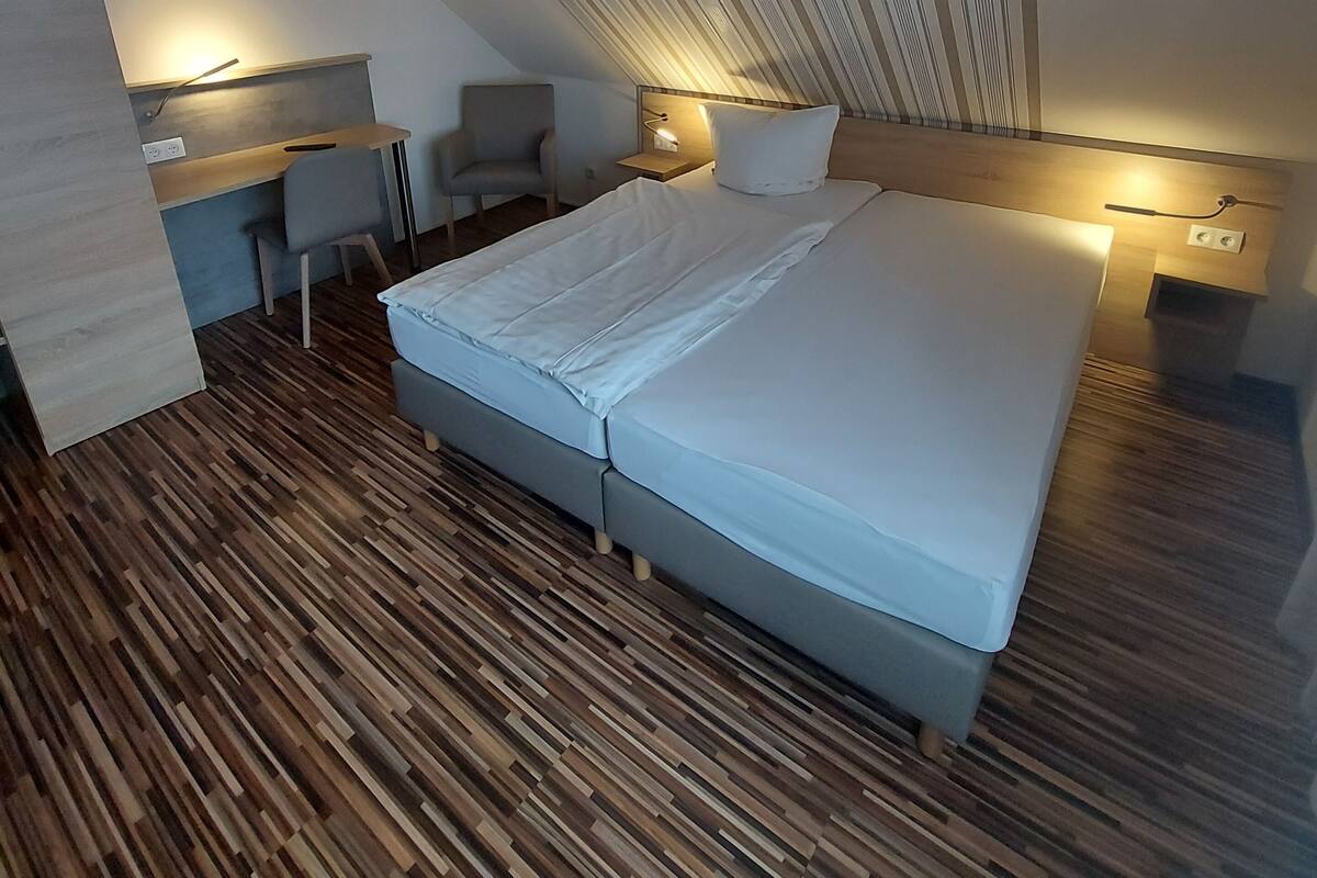 Une chambre moderne avec un plafond en pente, un grand lit, un bureau et une chaise.