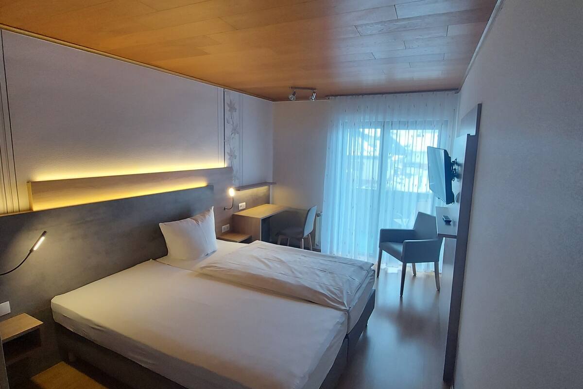 Une chambre d’hôtel moderne, dotée d’un grand lit, d’un bureau et d’une chaise.