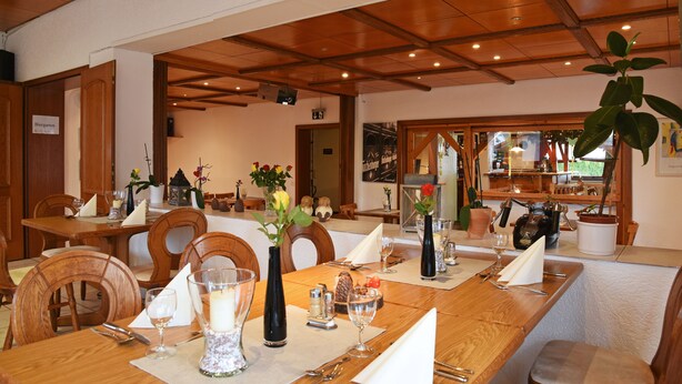 Un restaurant avec des tables et des chaises en bois, des bougies et des fleurs.
