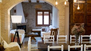 Una sala de estar acogedora con chimenea, muebles blancos y una mesa de comedor de vidrio.