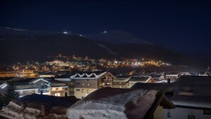 A snow-covered mountain town at night with illuminated buildings and a view of the mountain. - cervo (Livigno)