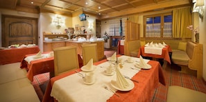 A dining area with tables set for a meal, a kitchen area with food items, and a cozy seating area with a sofa.