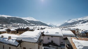 A snow-covered village with traditional buildings and a mountainous backdrop. - cervo (Livigno)
